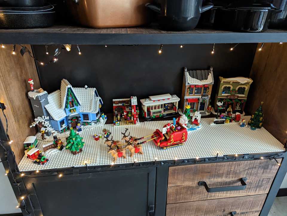 "A bookcase shelf filled with Lego Christmas builds"