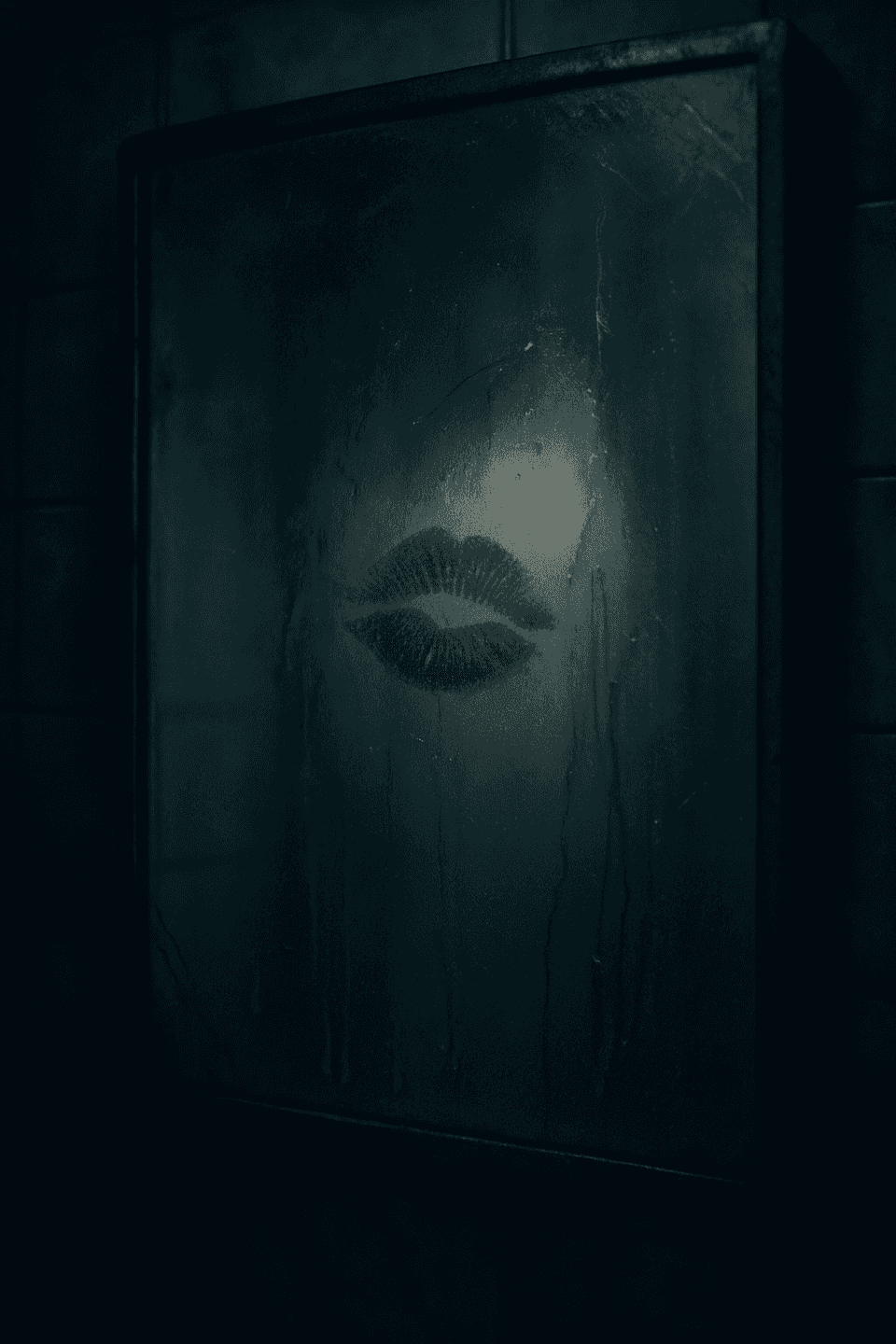 A foggy bathroom mirror with a red lipstick kiss at the center, surrounded by a shadowy, intimate atmosphere.